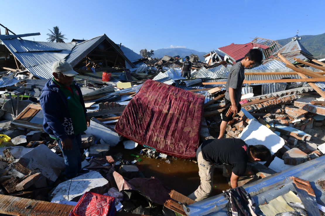 Des hommes recherchent toujours un membre de leur famille dans leur maison endommagée au village de Balaroa à Palu le 1er octobre 2018, suite au tremblement de terre et au tsunami qui ont frappé la région le 28 septembre.