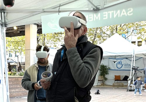 Un homme debout porte un casque de réalité virtuelle sur les yeux et une télécommande dans sa main droite
