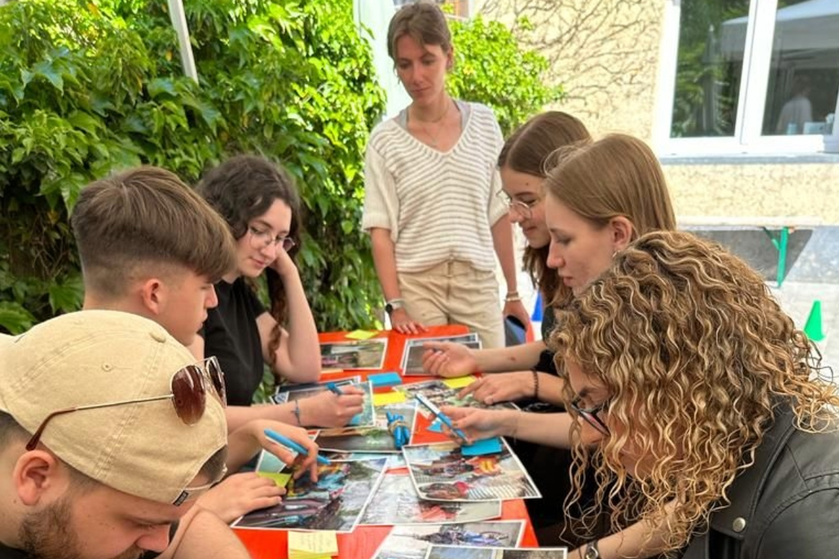 Des jeunes assis autour d'une table tiennent des stylos en main et regardent des photos sur le thème du handicap