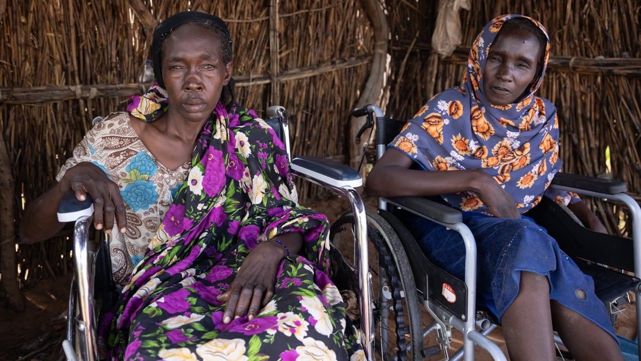 Deux femmes handicapées, en fauteuil roulant, fixent l'objectif.