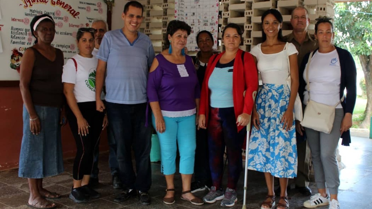 Sept personnes se tiennent debout les unes à côté des autres dans une pièce et sourient à la caméra.