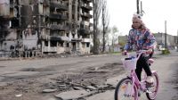 une petite fille fait du vélo devant des immeubles détruits par les bombardements à Borodyanka, en Ukraine