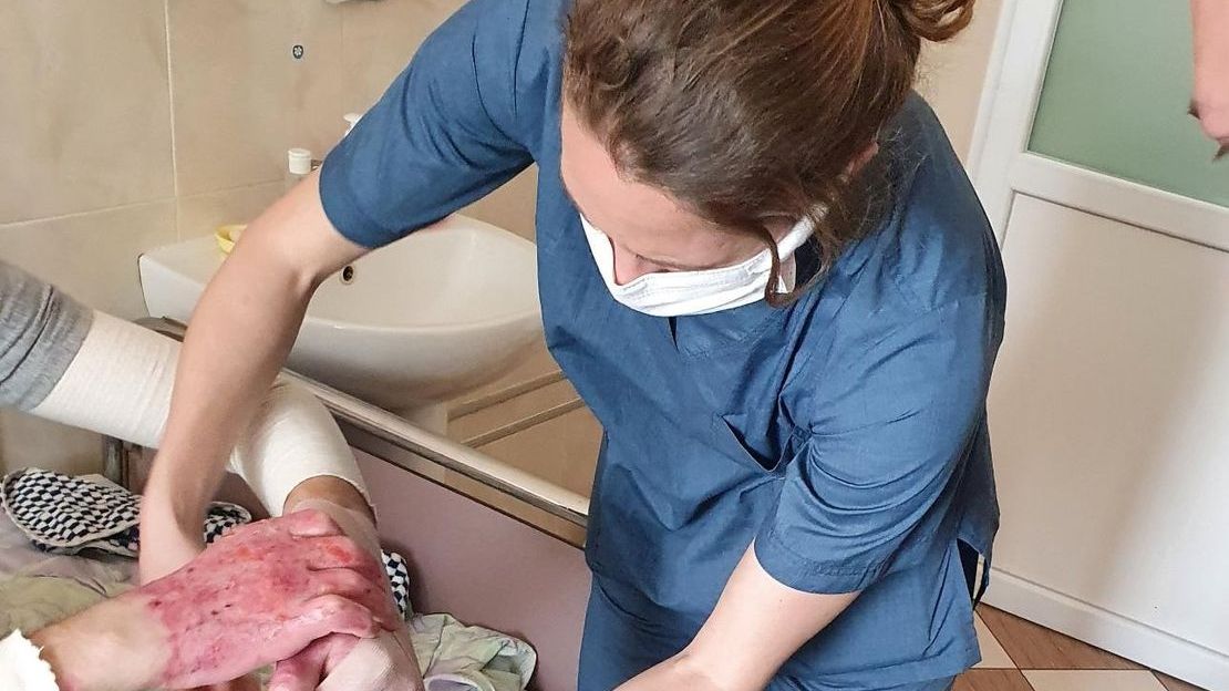 Kinésithérapeute pour Handicap International en Ukraine, Violette enroule des bandages autour d'un patient brûlé par une explosion.