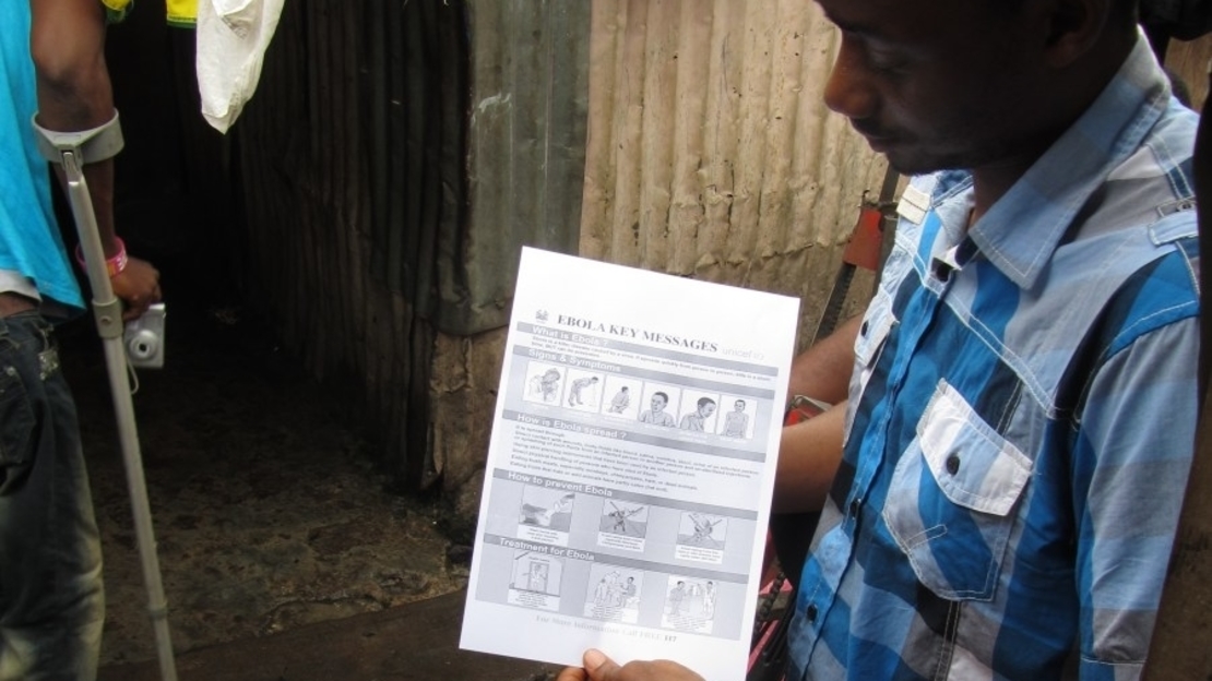 Séance de sensibilisation sur ebola à la « Maison de Jésus », une communauté située dans un bidonville. L'équipe de HI présente des informations à leur comité exécutif et leur donne les messages clés et du savon. 