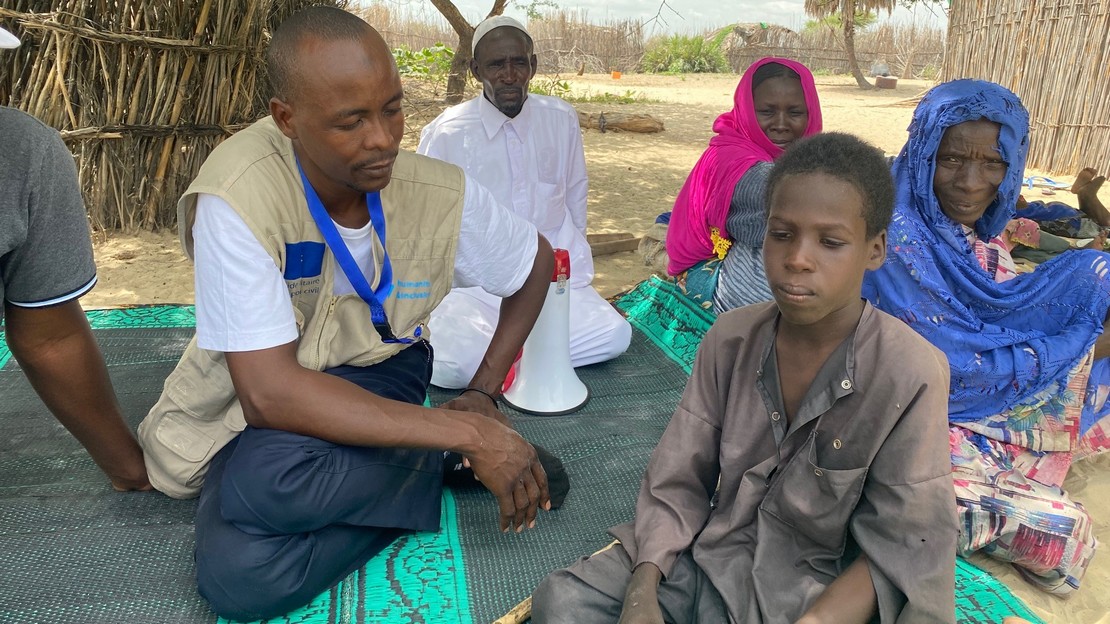 Une femme tient la main d'un enfant marchant dans la neige. à l'arrière plan, une famille avec des valises.