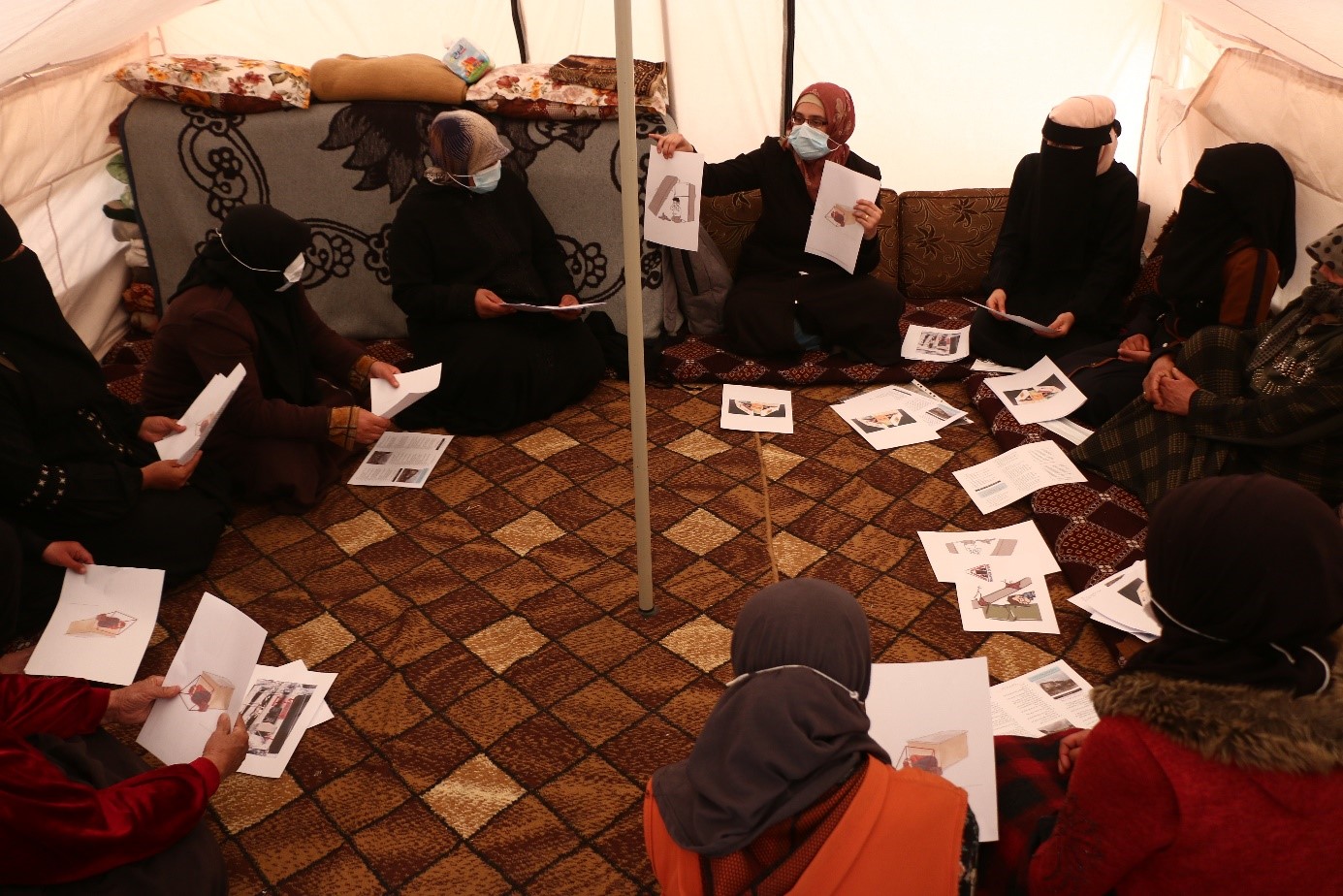 Des personnes assises en cercle avec des feuilles de papier dans les mains