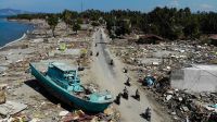 Le 1er octobre 2018, des personnes passent devant un bateau échoué et des bâtiments effondrés à Palu, après le tremblement de terre et le tsunami qui ont frappé la région le 28 septembre.