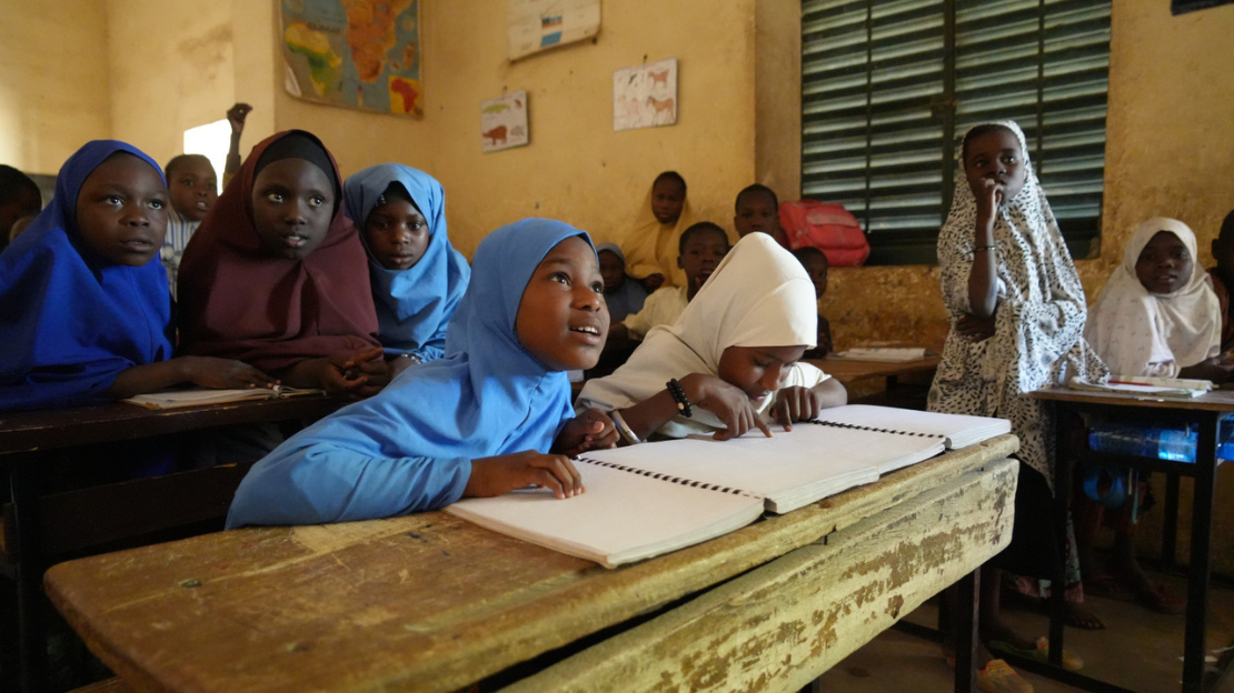 Des enfants noires sont assises derrière le table dans une salle de classe.