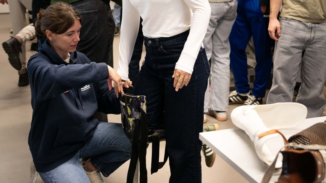 Leila, Chargée d’Éducation à la Citoyenneté Mondiale chez Handicap International Luxembourg, aide une participante à essayer une prothèse de jambe lors d’un atelier de sensibilisation.