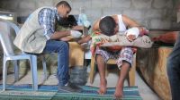 Un membre de HI soignant un homme Palestinien blessé à cause des bombardements durant la guerre en 2014