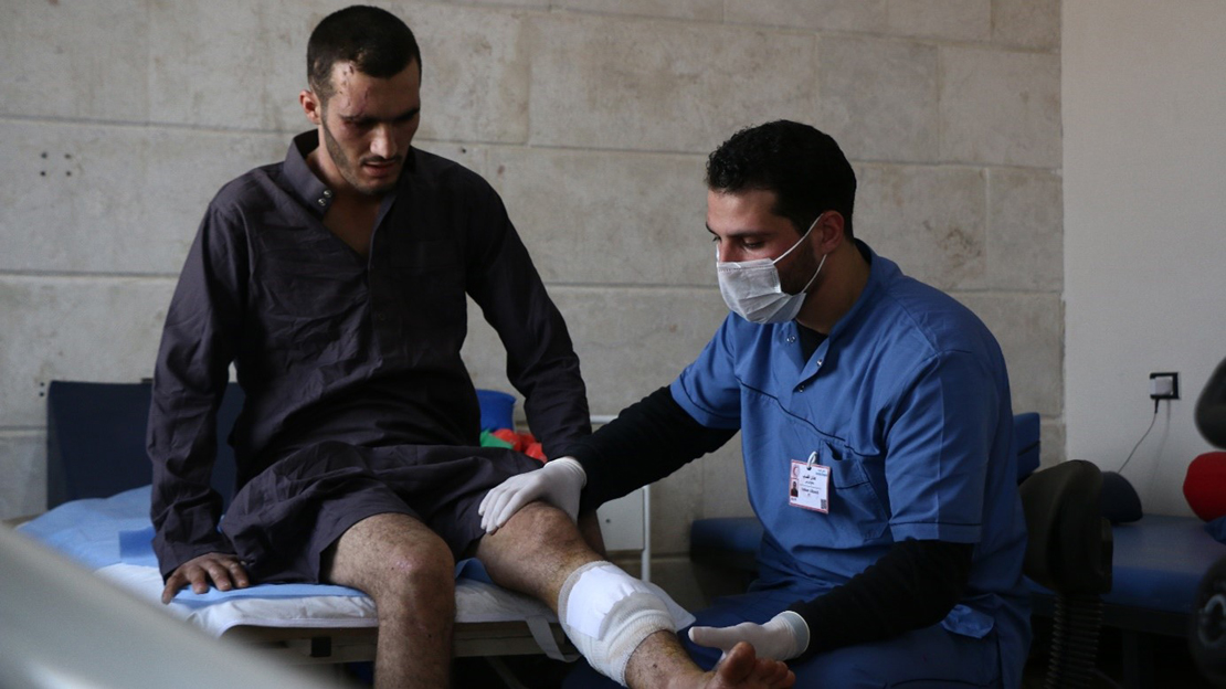 Un homme blessé à la jambe est examiné par un autre homme