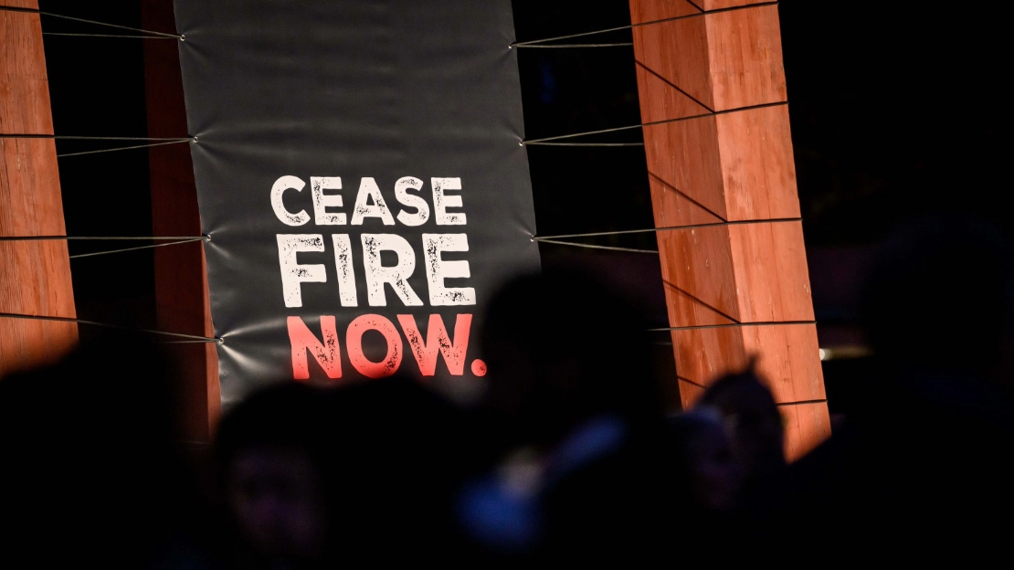 Une bâche tendue entre deux piliers avec le texte Cease Fire Now.