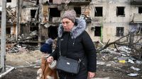 Une femme marche avec un enfant devant un bâtiment résidentiel endommagé dans la rue Koshytsa, une banlieue de la capitale ukrainienne Kiev, où un obus militaire a frappé, le 25 février 2022. Les forces russes ont atteint la périphérie de Kiev le vendredi 25 février 2022.