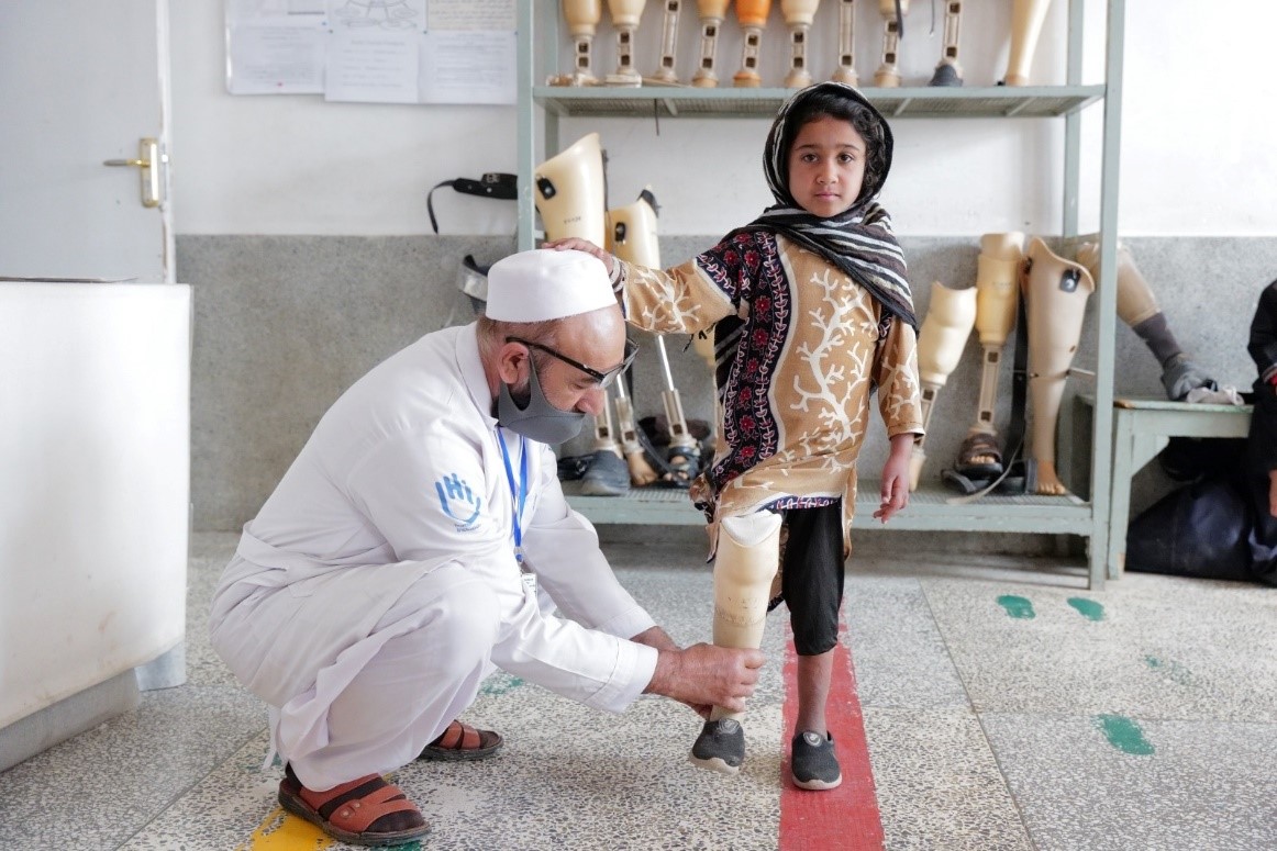 Une jeune fille avec une prothèse accompagnée d'un kinésithérapeute.