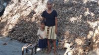 Devant leur maison, détruite par le cyclone Batsirai, Josephine se tient avec sa jeune fille. 