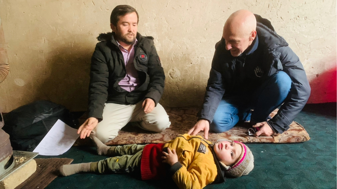 Deux hommes accroupis face à un enfant allongé