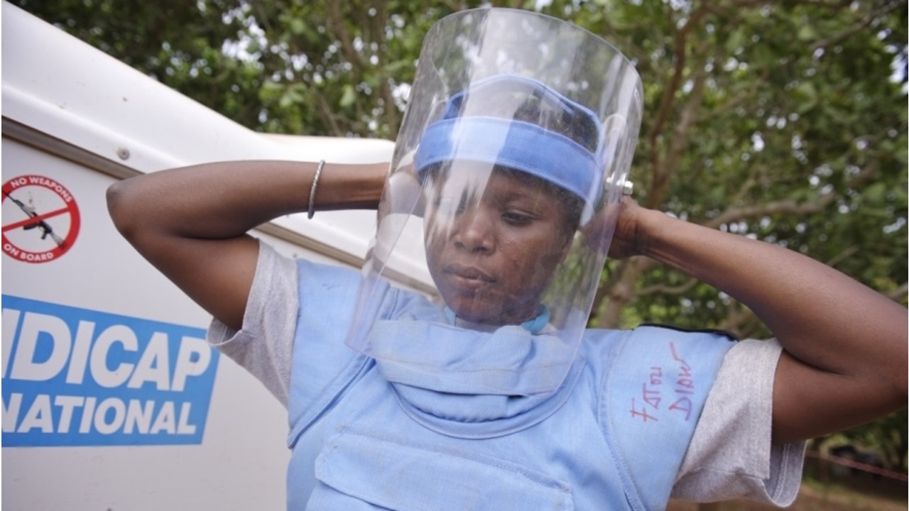  La démineuse Fatou Diaw en train de se préparer pour les activités de déminage. Elle met son casque et ses équipements de protection avant d'entrer en action.