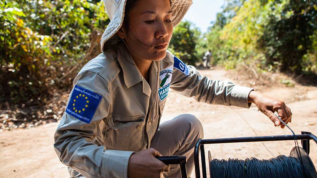 Lam Ngeung, démineuse, met en place le détonateur qui permet de faire exploser les sous-munitions à distance.