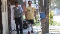 Un homme debout avec deux prothèses aux jambes se tenant à une rampe accompagné par un médecin.