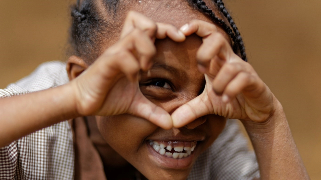 Une jeune fille formant un coeur avec ses mains