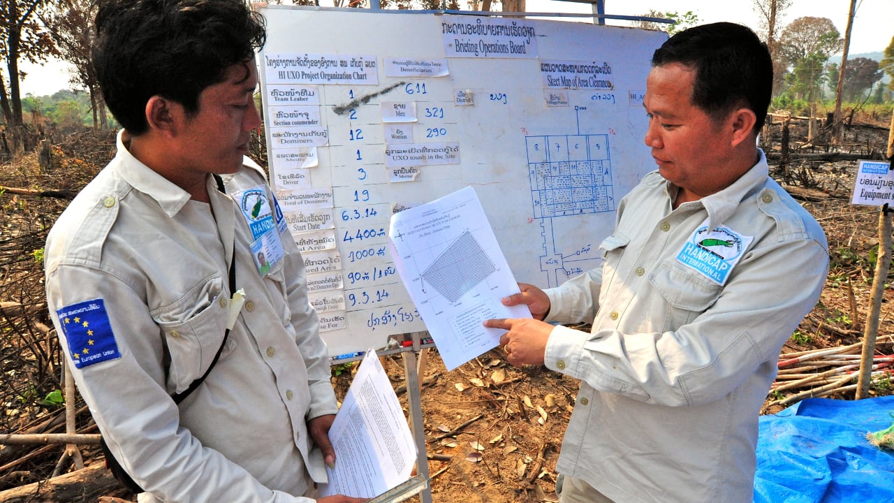 L’équipe de deminage de HI recherche des restes explosifs de guerre (REG), dans le village de Tamluang. Ils doivent dégager une zone où bientôt une école secondaire sera construite. 