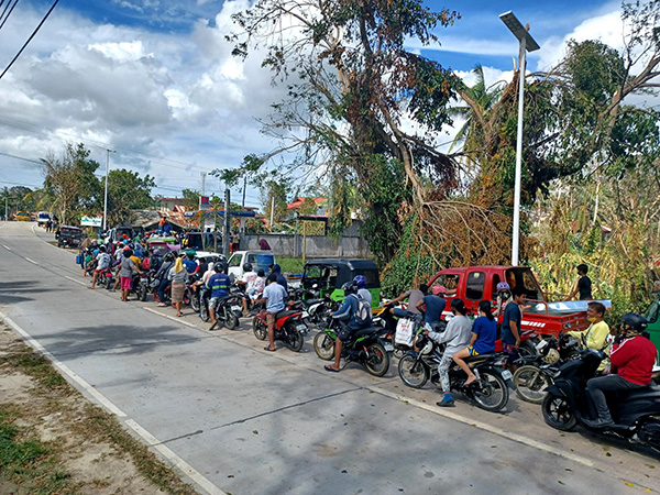 Une file d’attente pour acheter de l’essence, qui s’étend jusque dans la rue, après le passage du typhon Rai aux Philippines.